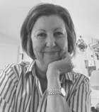 A smiling person with light blonde hair wearing a dark top hat and a scarf. The background has been removed, isolating the figure.